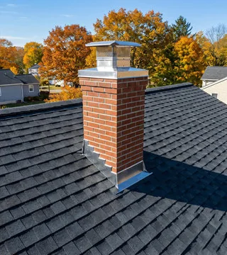 After: new red brick chimney with a stainless cap and fresh flashing on a dark shingle roof